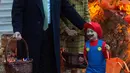 Presiden Amerika Serikat (AS) Donald Trump dan Ibu Negara Melania Trump memberikan permen kepada anak-anak selama yang hadir acara trick-or-treat pada perayaan Halloween di Gedung Putih, Washington, Minggu (28/10). (NICHOLAS KAMM / AFP)