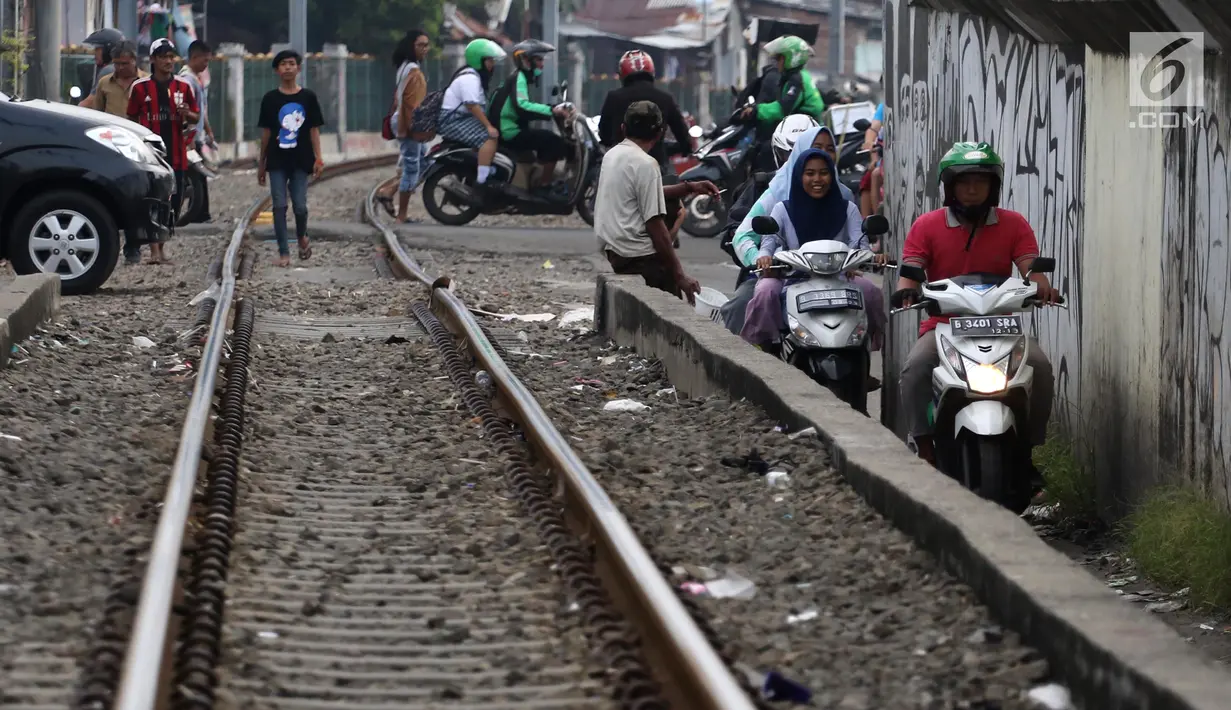 Pengendara melintas di samping rel kereta yang berada di kawasan Banjir Kanal Barat, Jakarta, Selasa (20/3). Selain mempersingkat waktu, pengendara beralasan hal itu demi memperpendek jarak tempuh. (Liputan6.com/Arya Manggala)