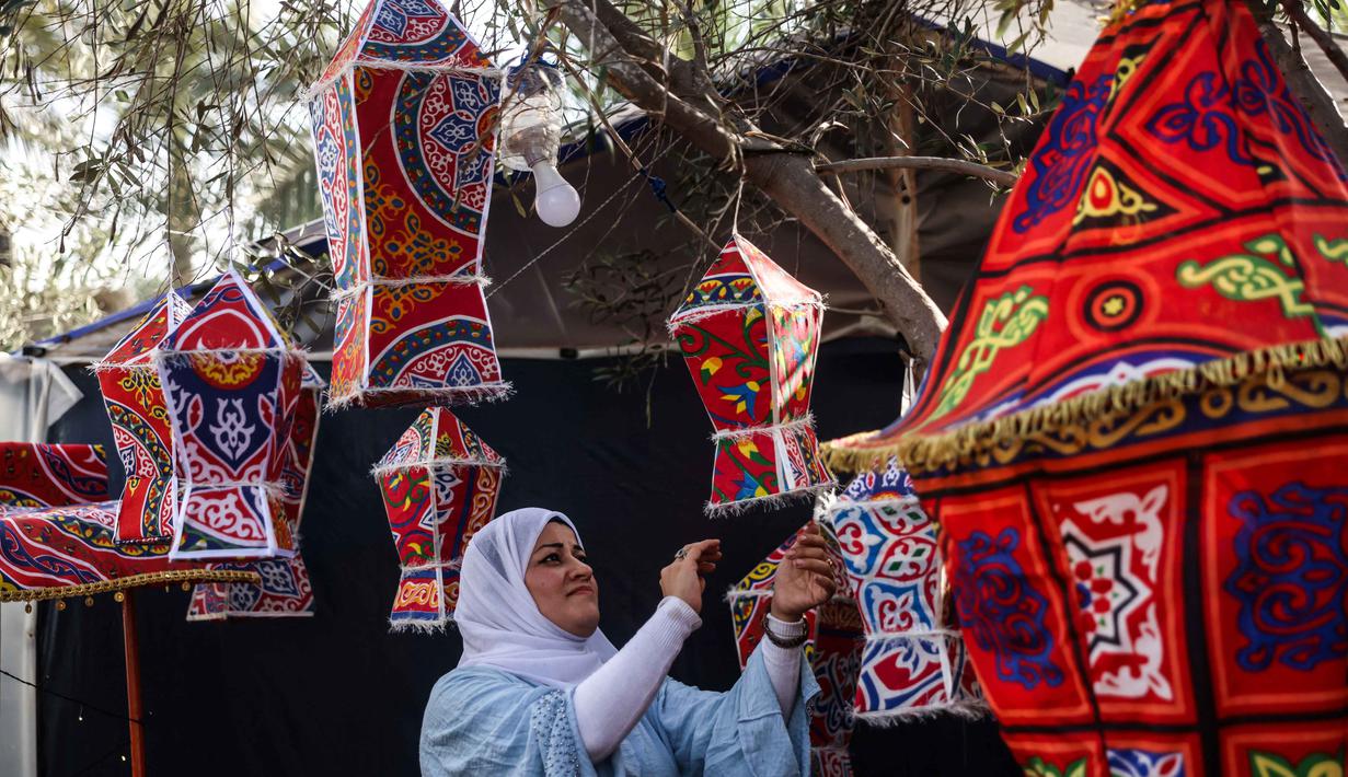 Fanous merupakan lentera tradisional berwarna-warni yang digunakan sebagai dekorasi khas untuk merayakan bulan suci Ramadan. Tampak dalam foto, Rehan Hazem Sharab, seorang warga Palestina berusia 32 tahun, membuat lampion buatan tangan dari kotak-kotak bantuan yang tersisa sebagai persiapan menyambut bulan suci Ramadan yang dimulai pada 17 Februari, di luar tendanya di lingkungan Al-Mawasi, Khan Younis, di Jalur Gaza selatan pada Sabtu 7 Februari 2026. (Bashar Taleb/AFP)
