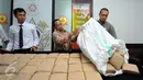 Petugas Dir IV Narkoba Mabes Polri membongkar karung berisi puluhan pak ganja saat rilis di Jakarta, Selasa (24/5/2016). Petugas menahan enam orang tersangka dengan barang bukti narkoba jenis ganja seberat satu ton. (Liputan6.com/Helmi Fithriansyah)