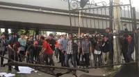 Massa HMI Unibos Makassar merusak pagar kantor Kejati Sulsel saat berunjuk rasa menagih keseriusan Kejati Sulsel menangkap buron kasus korupsi penyewaan lahan negara dan dugaan TPPU di Makassar, Jentang (Liputan6.com/ Eka Hakim)