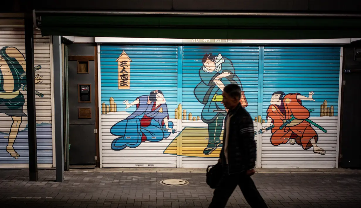 Seorang pria berjalan di jalan daerah Asakusa di Tokyo (1/12). Asakusa terkenal dengan Senso-ji , sebuah kuil Buddha khusus untuk Bodhisattva Kannon. (AFP Photo/Martin Bureau)