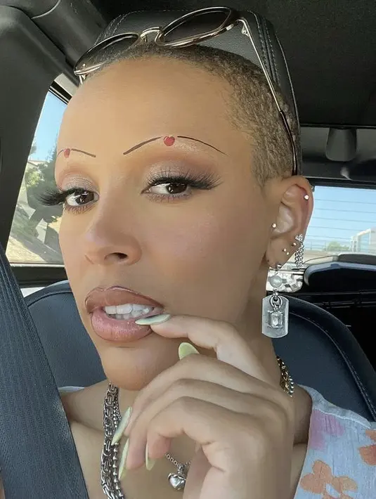 <p>Alis matanya pun nampak cute dengan gambar apel merah di kedua alisnya ditambah dengan garis hitam. Ia juga mengenakan eyeshadow tipis warna silver dan buku mata cukup panjang.@dojacat</p>