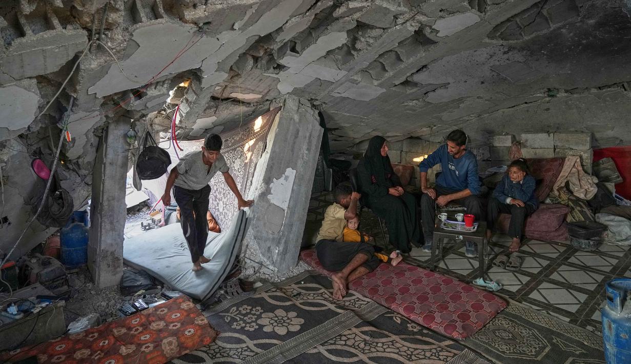 Perserikatan Bangsa Bangsa (PBB) pada Oktober 2025 memperkirakan 1,4 juta orang di Gaza sangat membutuhkan bantuan hunian darurat. Tampak dalam foto, Sahar Taroush berbicara dengan saudara laki-lakinya di rumahnya yang sebagian runtuh setelah kembali menyusul gencatan senjata terbaru, Jabaliya, Kota Gaza, Selasa, 11 November 2025. Terlihat juga anak-anaknya, Ammar paling kiri; Hassan dengan adik perempuannya yang berusia 2 tahun, Ahlam; dan Bisan, kanan. (AP Photo/Jehad Alshrafi)