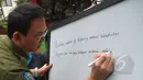 Gubernur DKI Basuki 'Ahok' Tjahaja Purnama menuliskan pesan di sebuah papan tulis saat meninjau hari pertama pelaksanaan ujian nasional (UN) di SMKN 27 Jakarta, Senin (13/4/2015). (Liputan6.com/Herman Zakharia)