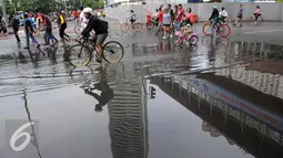 Kegiatan Car Free Day di Jakarta tetap ramai walau hujan mengguyur sejak semalam, Minggu (24/1/2016). Genangan air masih tersisa di jalan sekitar kawasan Car Free Day. (Liputan6.com/Helmi Affandi)