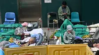 Orang-orang berbaring di ranjang rumah sakit di luar Caritas Medical Centre, Hong Kong, Rabu (16/2/2022). Hong Kong menghadapi gelombang virus corona COVID-19 terburuk hingga saat ini. (Peter PARKS/AFP)