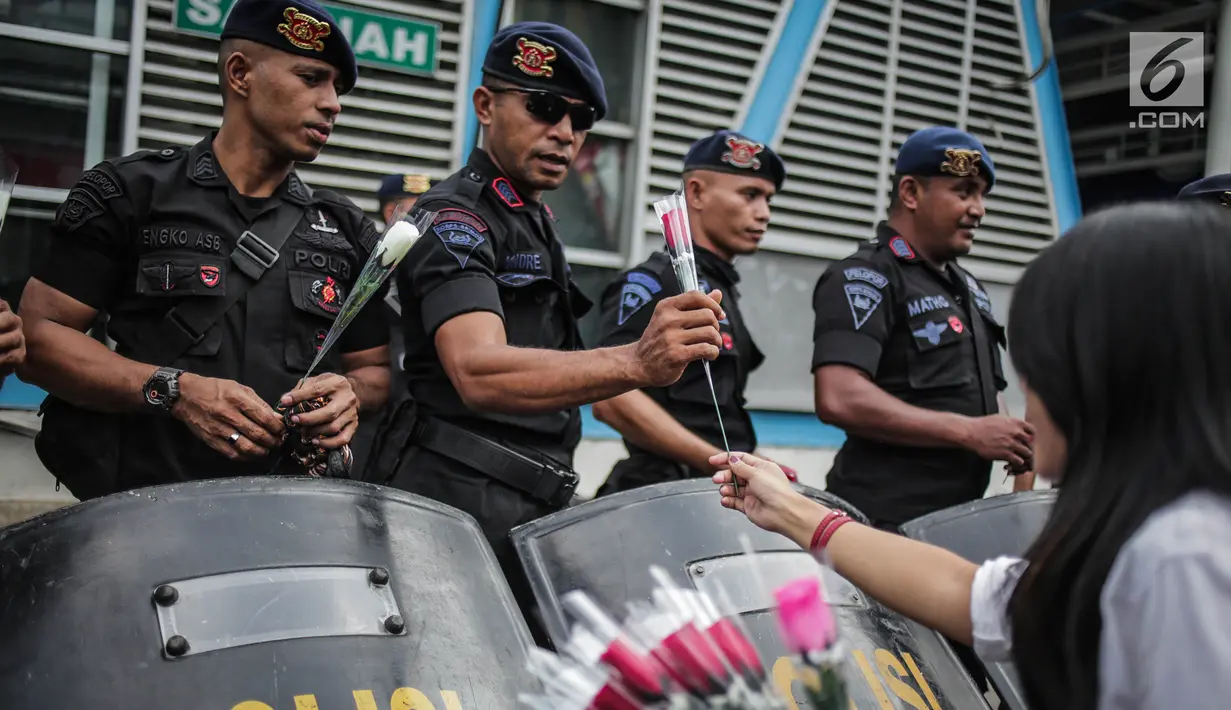 Petugas Brimob menerima bunga dari peserta aksi komunitas Spartan Nusantara di sekitar Gedung Bawaslu, Jakarta, Minggu (26/5/2019). Aksi tersebut sebagai bentuk terima kasih kepada TNI/Polri karena setia dan menjaga keamanan NKRI terkait sengketa pemilu. (Liputan6.com/Faizal Fanani)