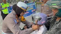 Kasat Lantas Polres Pelalawan AKP Akira Ceria memberikan helm kepada anak-anak dalam rangka Operasi Keselamatan Lancang Kuning jelang Ramadan. (Liputan6.com/M Syukur)