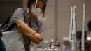 Seorang jurnalis yang mengenakan masker untuk mencegah penularan COVID-19 menaruh sampel air liur harian saat tes PCR di Pusat Media Olimpiade Tokyo 2020, Tokyo, Jepang, 20 Juli 2021. Jurnalis yang akan meliput Olimpiade Tokyo 2020 harus menjalani protokol kesehatan ketat. (Franck FIFE/AFP)