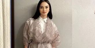 Ririn tampil mengenakam outer lace dengan bordiran warna cokelat yang memiliki detail belt. Dipadukan inner kemeja putih dan celananya. Credit: Instagram (@ririnekawati)