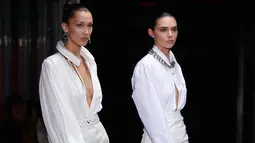 Model Bella Hadid dan Kendall Jenner berjalan di atas catwalk memakai busana Off White Spring/Summer 2019 selama Paris Fashion Week, Prancis (27/9). Kedua model tersebut tampil cantik membawakan koleksi rancangan Virgil Abloh. (AP Photo/Thibault Camus)