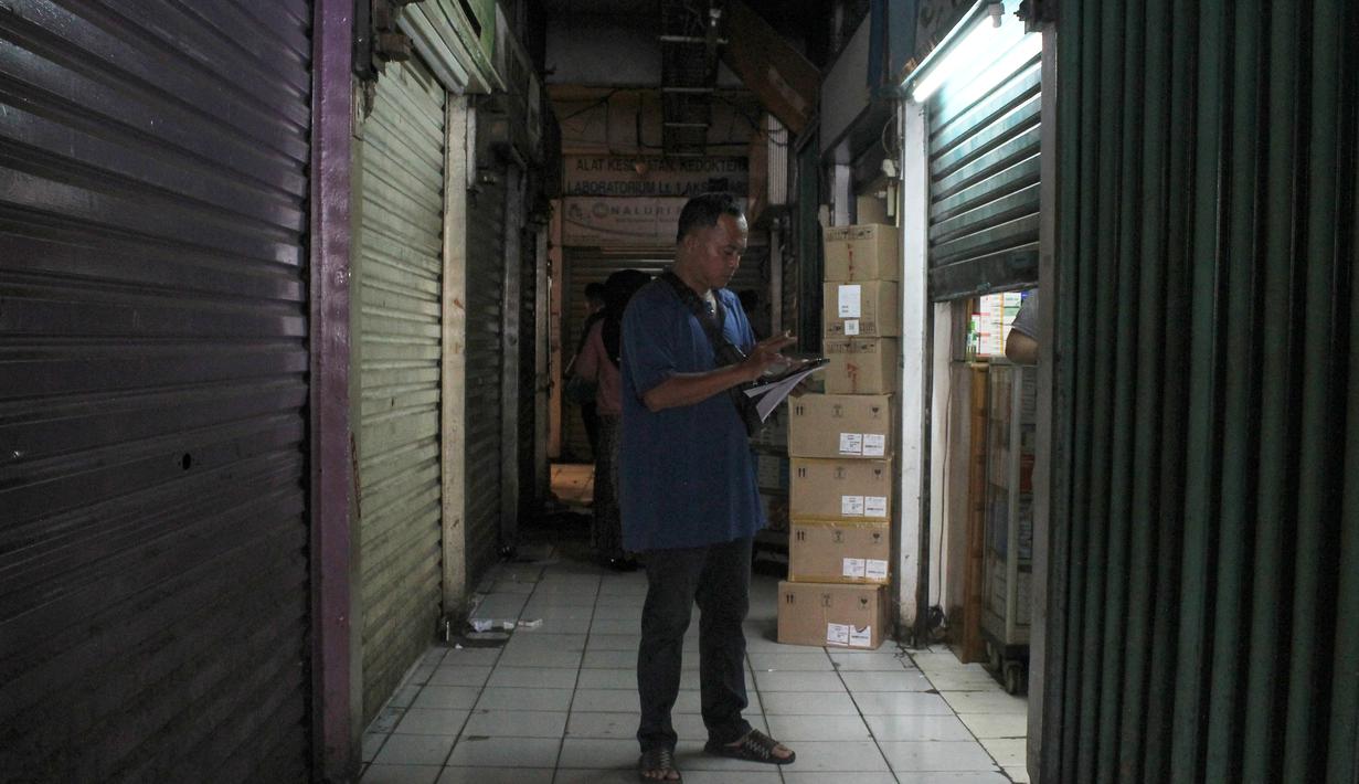 Sebagai bentuk solidaritas, banyak pedagang memilih menutup toko mereka. Tampak dalam foto, salah satu pedagang memeriksa kios di dalam Pasar Pramuka, Jakarta Timur, Jumat (14/11/2025). (merdeka.com/magang/Rendi Saputra)