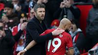 Pelatih interim Manchester United, Michael Carrick, memberi ucapan selamat kepada gelandang asal Kamerun Bryan Mbeumo saat meninggalkan lapangan setelah ditarik keluar dalam pertandingan Liga Inggris antara Manchester United dan Manchester City di Old Trafford, Manchester, Sabtu (17/1/2026). (Darren Staples / AFP)