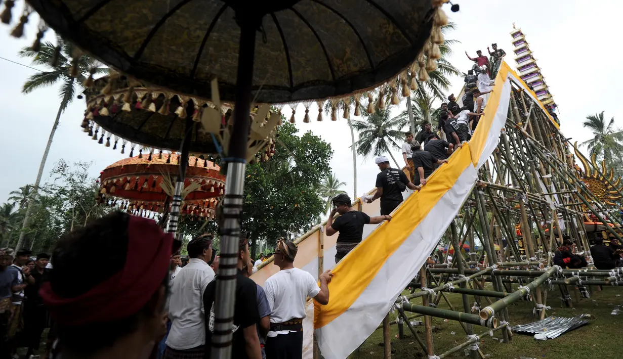 Sejumlah warga menyiapkan arak-arakan Bade atau menara bertingkat sembilan yang berisi jenazah anggota keluarga dari pahlawan nasional I Gusti Ngurah Rai dalam prosesi upacara Ngaben di Desa Carangsari, Badung, Bali, Senin (29/4/2019). (SONNY TUMBELAKA/AFP)