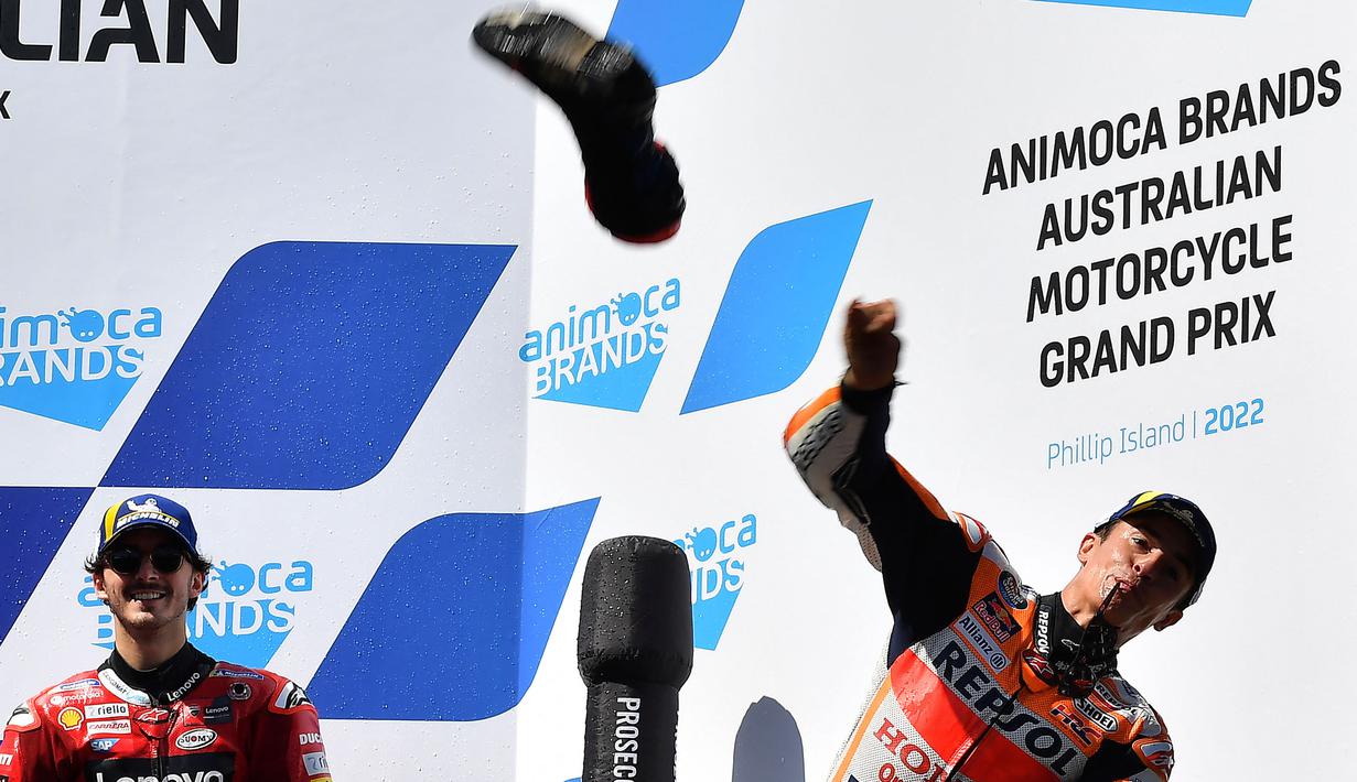 Pembalap Spanyol dari tim Repsol Honda, Marc Marquez (kanan) melempar sepatunya ke arah para penggemar usai Grand Prix MotoGP Australia di Sirkuit Phillip Island, Minggu (16/10/2022). Marc Marquez finish di posisi kedua dan ini menjadi podium pertamanya sejak kembali pasca operasi keempat cedera patah lengan tangan kanan. (Paul CROCK/AFP)