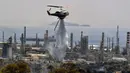 <p>Helikopter pemadam kebakaran menyemprotkan air saat terjadi kebakaran hutan dekat kilang minyak di Agioi Theodoroi. (Valerie GACHE/AFP)</p>