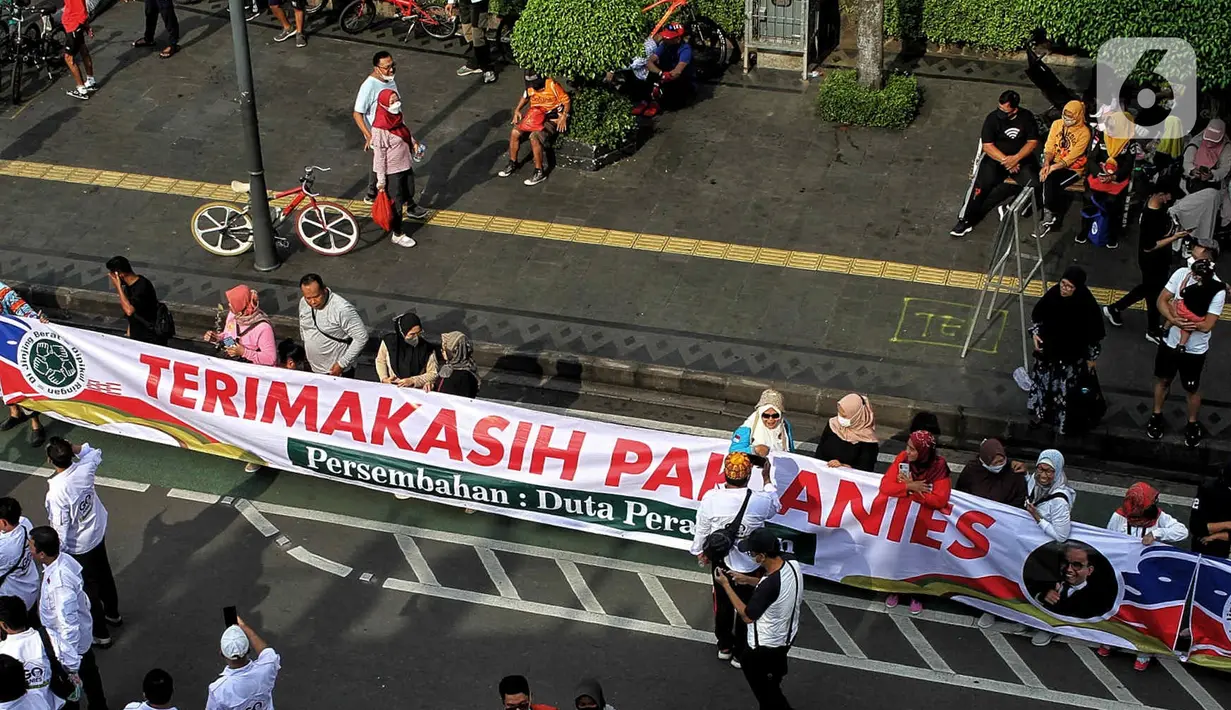 Warga membentangkan spanduk bertuliskan terimakasih Anies Baswedan di kawasan Bundaran HI, Jakarta, Minggu (16/10/2022). Hari terkahir menjabat sebagai Gubernur, Anies berkeliling dengan sepeda menuju Balai Kota. (Liputan6.com/Angga Yuniar)