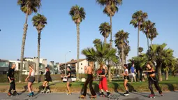 Orang-orang bermain sepatu roda di sepanjang Venice Beach di Venice, California, Kamis (3/9/2020). Permintaan sepatu roda di Amerika Serikat mengalami peningkatan tajam untuk mencari aktivitas di luar ruangan di tengah pembatasan sosial akibat corona Covid-19. (Mario Tama/Getty Images/AFP)