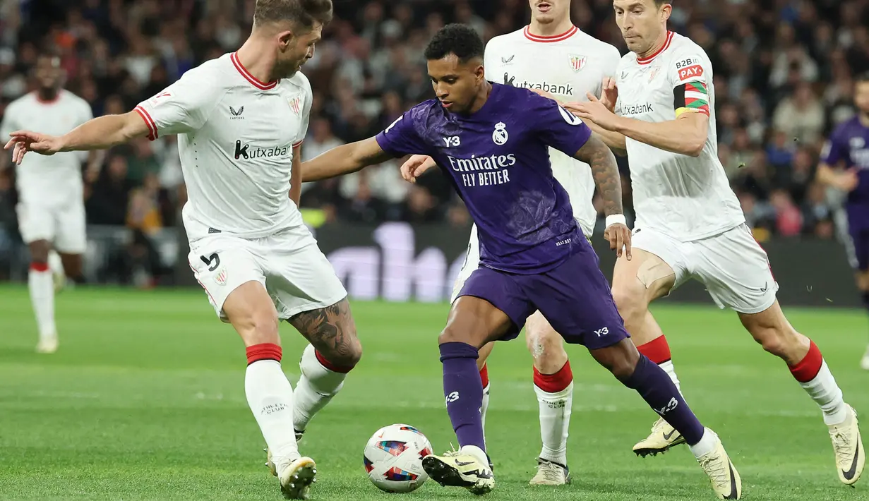 Pemain Real Madrid, Rodrygo, berusaha melewati pemain Athletic Bilbao pada laga Liga Spanyol di Stadion Santiago Bernabeu, Minggu (31/3/2024). (AFP/Pierre-Philippe Marcou)