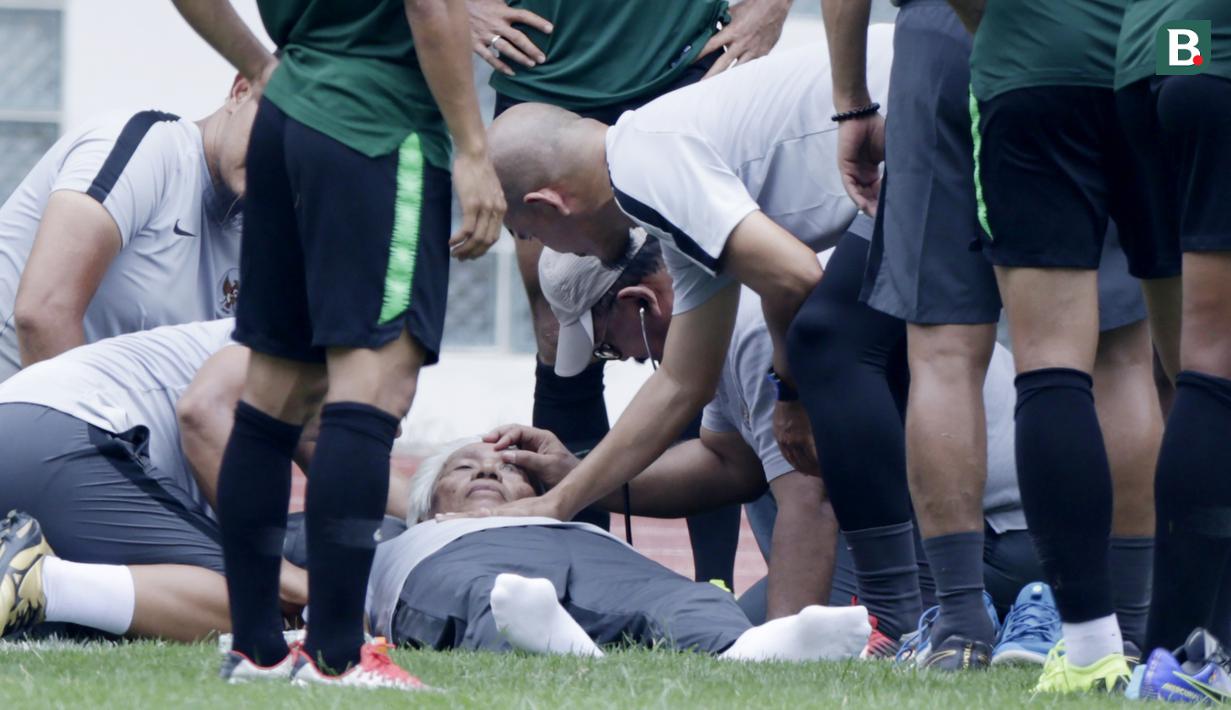 Dokter Timnas Indonesia, Syarif Alwi, memeriksa Danurwindo, yang pingsan usai memantau latihan di Stadion Wibawa Mukti, Jawa Barat, Sabtu (03/11/2018). Danurwindo ambruk ketika tim dan ofisial melakukan sesi foto bersama. (Bola.com/M Iqbal Ichsan)