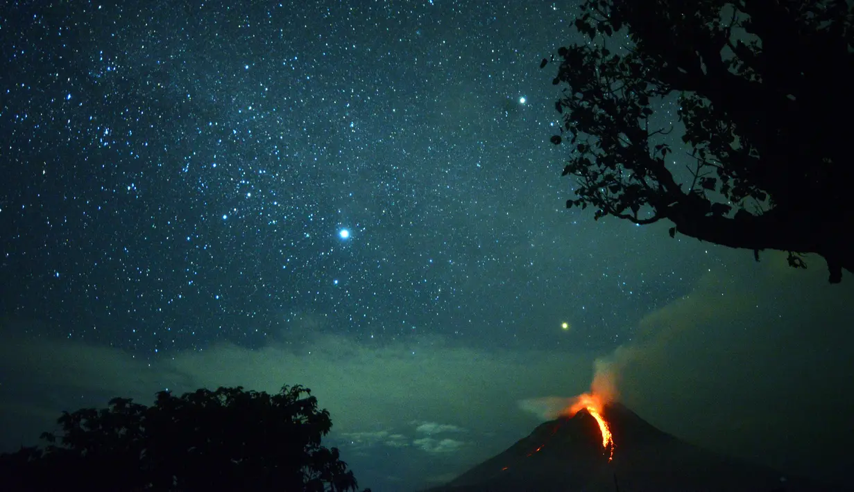 Pemandangan saat Gunung Sinabung memuntahkan lahar dan langit diterangi cahaya bintang di Karo, Sumatera Utara (28/12). Gunung Api Sinabung yang masih berstatus awas level empat kembali erupsi pada Rabu (27/12) sore. (AFP/Lana Priatna)