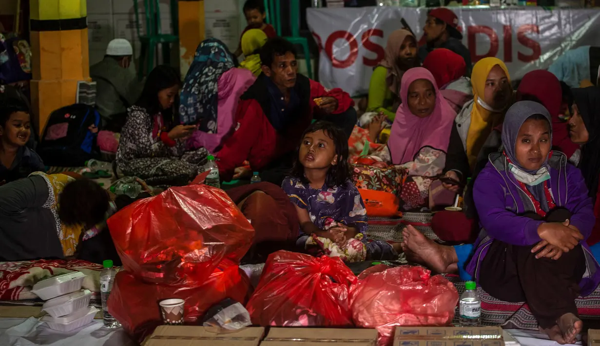 Warga berkumpul di pusat evakuasi erupsi Gunung Semeru di Desa Sumber Wuluh, Lumajang, Jawa Timur, 5 Desember 2021. Ribuan warga mengungsi ke masjid, sekolah dan kantor desa, serta di titik-titik yang dianggap aman. (Juni Kriswanto/AFP)