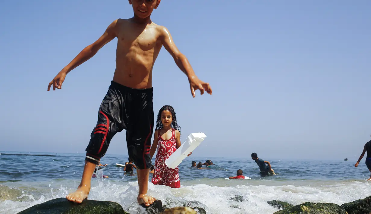Anak-anak Palestina saat bermain bersama di laut Mediterania dekat kamp pengungsi al-Shati di Kota Gaza (3/7). (AFP Photo/Mohammed Abed)