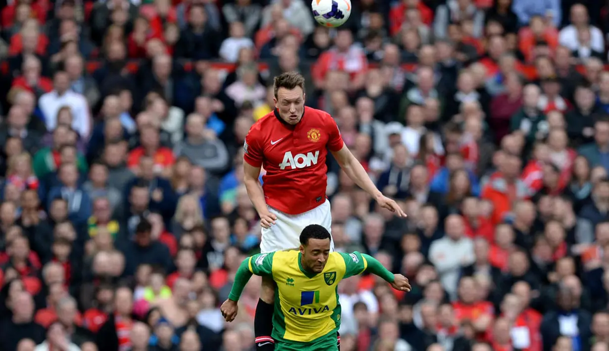 Gelandang bertahan Manchester United, Phil Jones (atas) mencoba memenangkan perebutan bola atas dari Nathan Redmond (Norwich City) di laga lanjutan Liga Primer Inggris di stadion Old Trafford (27/4/2014). (REUTERS/Nigel Roddis)