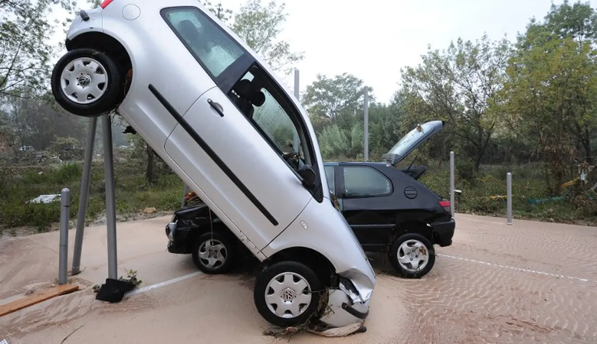 Selain di pohon, beberapa mobil penduduk yang lain juga tersangkut pada tiang besi di kawasan Grabels, Prancis, Selasa (7/10/2014) (AFP PHOTO/Sylvain THOMAS)