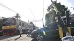 Kereta melintasi perlintasan kereta api di Jalan Duri Kosambi Raya, Jakarta, Rabu (15/1/2020). Warga setempat terpaksa membangun palang secara swadaya dan mengatur lalu lintas akibat perlintasan kereta di dekat Stasiun Rawa Buaya itu belum dipasang palang pintu otomatis. (merdeka.com/Iqbal Nugroho)