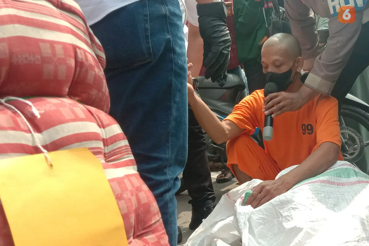 Pelaku Memeragakan Memasukkan Jenazah Istrinya Ke Dalam Karung. (Selasa, 02/08/2022). (Yandhi Deslatama/Liputan6.com).