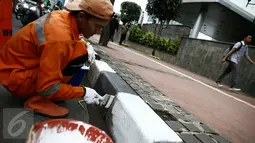 Petugas dari Kelurahan Karet Semanggi mengecat trotoar di kawasan Jalan Semanggi, Jakarta, Selasa (1/3/2016). Trotoar itu dipercantik dengan dicat ulang oleh Petugas Prasarana Sarana Umum (PPSU). (Liputan6.com/Faizal Fanani)