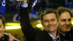 Pelatih Chelsea, Jose Mourinho tersenyum mengangkat trofi Piala Carling setelah mengalahkan Liverpool di final Piala Carling di Millennium Dome, Cardiff, Wales, 27 Februari 2005. Eks pelatih MU, Real Madrid dan Inter Milan itu dikontrak panjang hingga musim panas 2023. (AFP/Rebecca Naden)