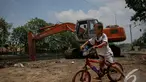 Seorang bocah bersepeda asyik memperhatikan pengerukan Kali Sidang, Jakarta, Jumat (19/9/2014) (Liputan6.com/Faizal Fanani)