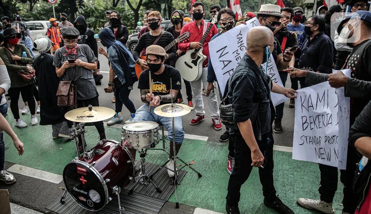 Sejumlah musisi kafe saat melaksanakan aksi di depan Balai Kota Jakarta, Rabu (8/7/2020). Aksi ngamen di depan Balai Kota Jakarta yang diikuti oleh musisi kafe itu untuk menyuarakan aspirasi pekerja seni harian yang terdampak mata pencahariannya selama masa PSBB. (Liputan6.com/Faizal Fanani)