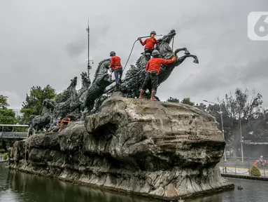 Aktivitas pembersihan dan perawatan patung kuda Arjuna Wijaya di Jalan Medan Merdeka, Jakarta, Rabu (27/1/2021). Patung yang dibangun sejak 1987 karya pematung Nyoman Nuarta tersebut dibersihkan dan ditata kembali untuk memperindah kota. (Liputan6.com/Faizal Fanani)