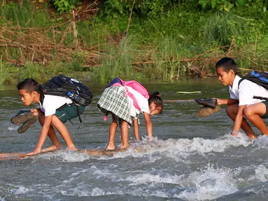 Sejumlah bocah menyeberangi sungai menggunakan perahu rakit untuk berangkat sekolah di Montalban, Rizal timur laut dari Manila, Filipina (13/6). Tidak adanya fasilitas jembatan membuat para siswa mempertaruhkan keselamatannya. (REUTERS/Erik De Castro)