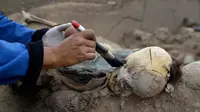 Arkeolog membersihkan kerangka manusia di bekas situs suci pra-Kerajaan Inka yang baru ditemukan di Lima, Kamis (24/8). Menurut Kementerian Kebudayaan Peru, imigran China pada masa itu tidak dapat dikuburkan di pemakaman Katolik. (AP Photo/Martin Mejia)