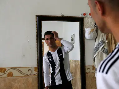 Pemain sepak bola Kurdi Irak, Biwar Abdullah (25) melihat ke sebuah cermin di rumahnya distrik Soran, timur laut Erbil, 6 April 2019. Biwar Abdullah menjadi selebritis dadakan dan terkenal karena kemiripan wajahnya dengan bintang Juventus, Cristiano Ronaldo. (REUTERS/Azad Lashkari)