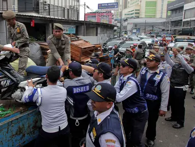 Petugas Satpol PP menertibkan dan mengangkut lapak pedagang kaki lima (PKL) di Pasar Tanah Abang, Jakarta, Kamis (4/5). Penertiban dilakukan agar tidak menggangu fungsi pedestrian untuk pejalan kaki. (Liputan6.com/Johan Tallo)