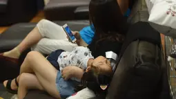 Seorang anak tidur di sebuah pusat perbelanjaan menghindari panas di luar di Hangzhou, di provinsi Zhejiang timur China (24/7). Beberapa pekan terakhir China mengalami suhu udara yang cukup panas. (AFP Photo/Str/China Out)