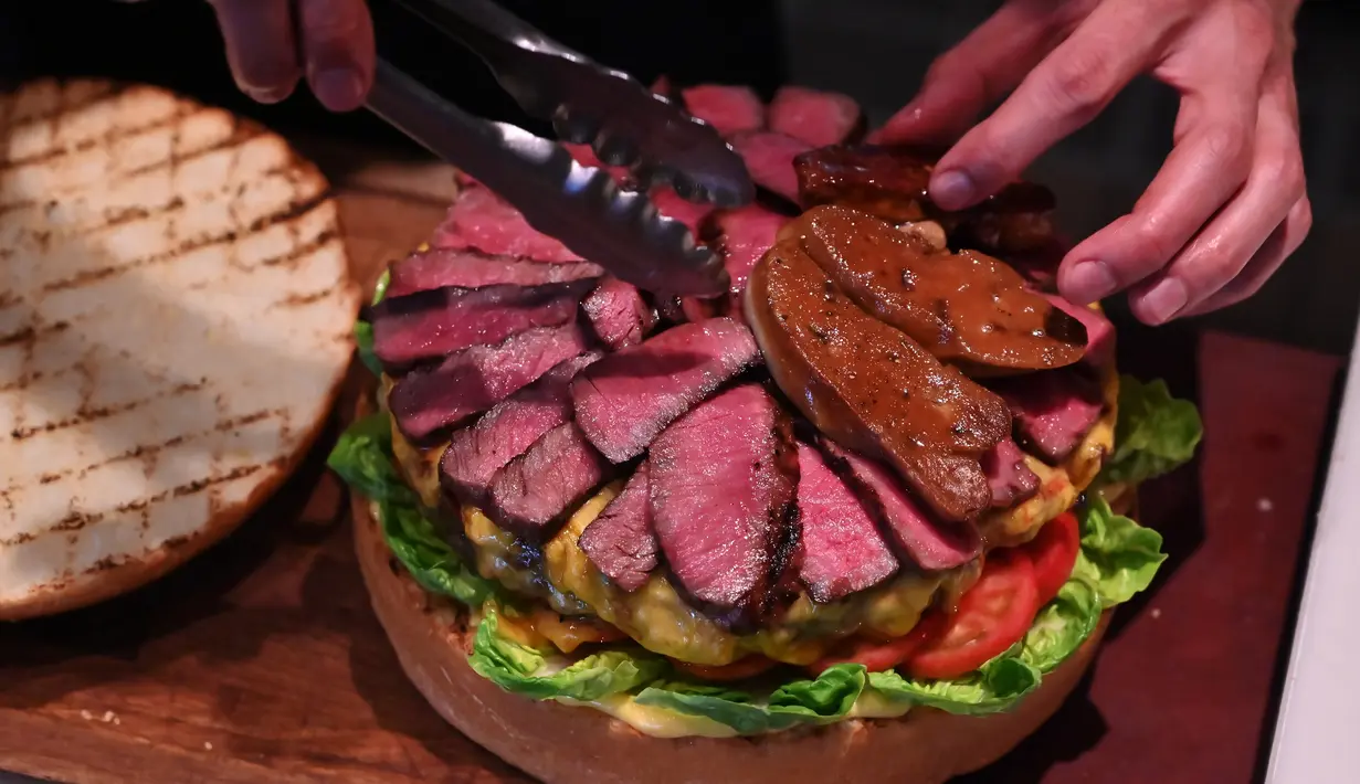 Chef dari restoran The Oak Door, Patrick Shimada membuat burger raksasa di hotel Grand Hyatt Tokyo, Senin (1/4). Hamburger ini memiliki diameter 25 centimeter dan berisi foie gras, daging sapi Jepang, dan jamur truffle hitam segar. (CHARLY TRIBALLEAU/AFP)