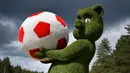Sebuah patung anak beruang memegang bola yang terbuat dari dedaunan terlihat di dekat bandara Samara, Rusia (11/6). Rusia akan menjadi tuan rumah turnamen sepak bola Piala Dunia 2018. (AFP Photo/Fabrice Coffrini)