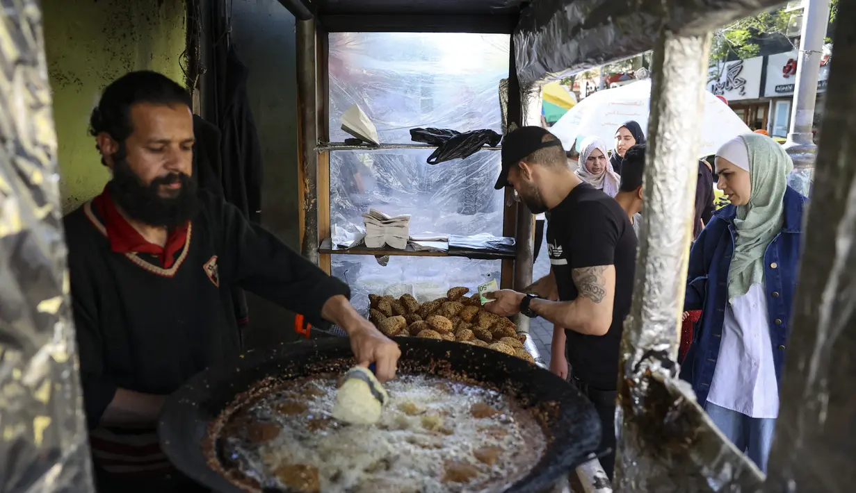 Warga Palestina membuat falafel, makanan yang disukai untuk berbuka puasa, selama bulan suci Ramadhan di pusat kota Hebron di Tepi Barat yang diduduki (9/4/2022). Falafel adalah sebuah makanan Timur Tengah. (AFP/Hazem Bader)
