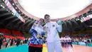 Meski begitu, keduanya tetap fokus memberikan usaha yang terbaik untuk timnas mereka. Tampak dalam foto, pevoli Indonesia Alfin Daniel Pratama (kanan) berfoto bersama dengan kekasihnya yang juga penerjemah Timnas voli putra Thailand, McEntee Catherine, di di Stadion Indoor Hua Mak, Jumat (19/12/2025). (Bola.com/Bagaskara Lazuardi)