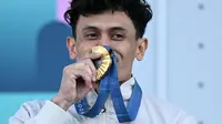 Atlet panjat tebing Indonesia, Veddriq Leonardo mencium medali emasnya saat di atas podium cabang olahraga panjat tebing nomor speed Olimpiade Paris 2024 di Le Bourget Sport Climbing Venue, Paris, Prancis, Kamis (08/08/2024). (AFP/Jonathan Nackstrand)