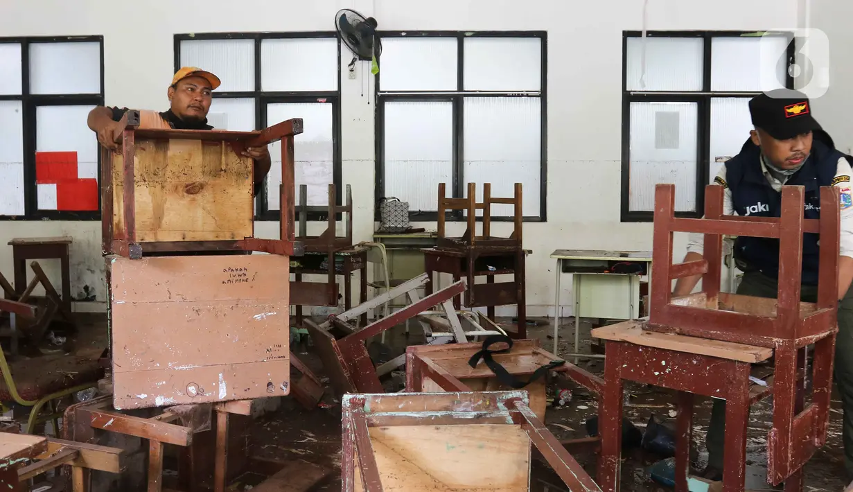 Petugas menata meja dan kursi saat membersihkan ruangan di MTsN 19 Pondok Labu, Jakarta, Jumat (7/10/2022). Petugas PPSU, Satpol PP, dan Dinas Pemadam Kebakaran membersihkan ruang kelas, kantin, dan fasilitas lainnya usai terendam banjir pada Kamis sore kemarin. (Liputan6.com/Herman Zakharia)