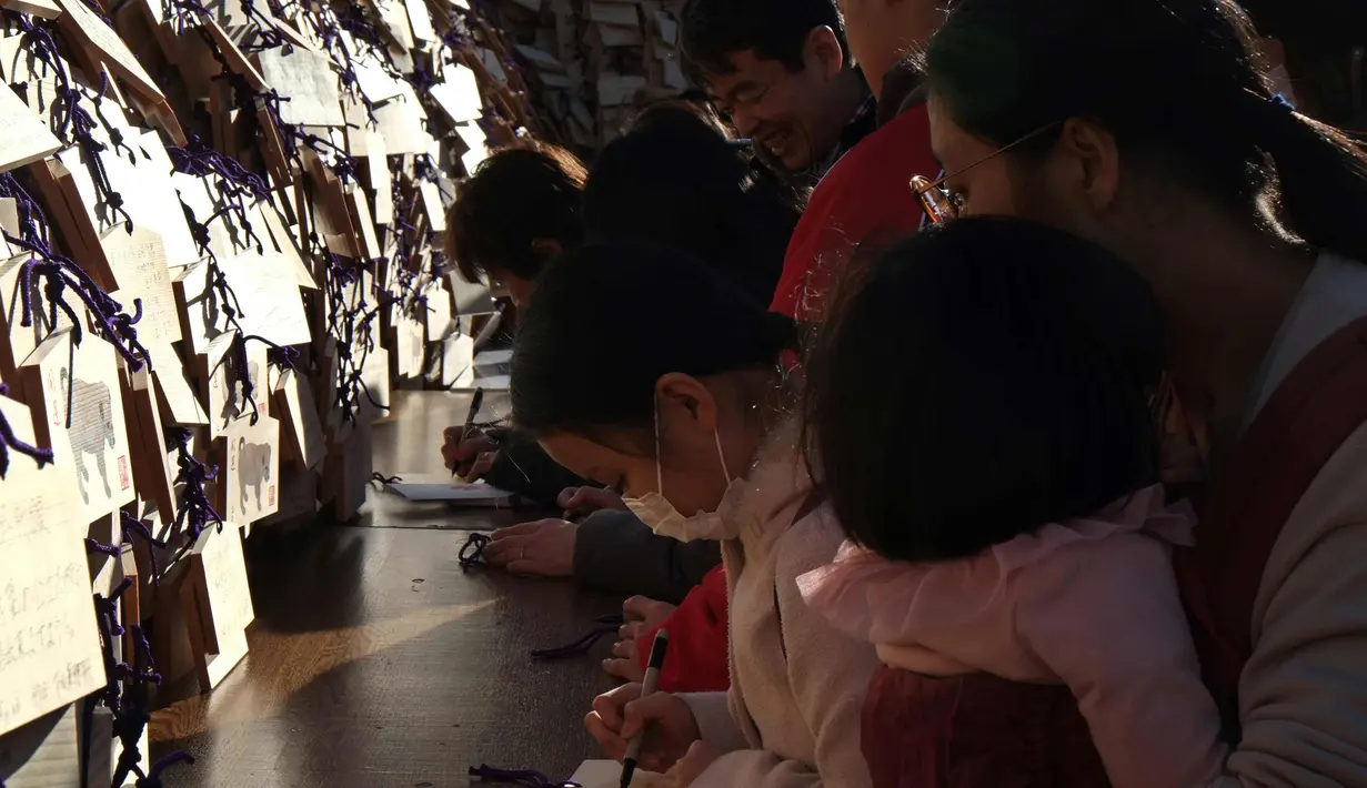 Pelajar menulis harapan mereka di atas papan Ema di Kuil Yushima Tenmangu, Tokyo, Jepang, (7/1). Mereka menuliskan harapan di atas papan Ema agar diberikan kemudahan dalam menghadapi ujian masuk sekolah tahun ini. (AFP Photo/Kazuhiro Nogi)
