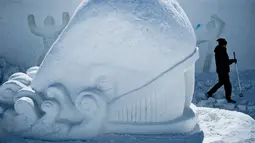 Seorang seniman mengukir patung es raksasa berbentuk ikan di Snow Land, PyeongChang, Korea Selatan, Senin (5/2). (Brendan Smialowski/AFP)